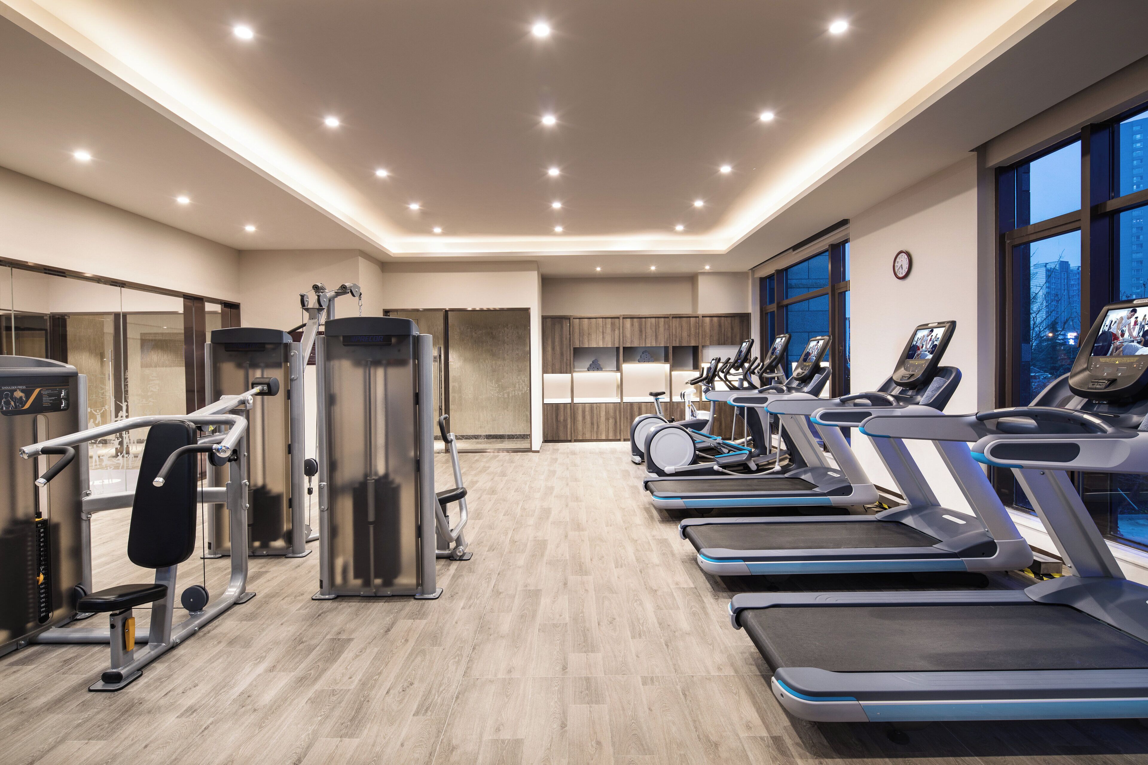 A modern gym with treadmills, weight machines, and a large mirror.