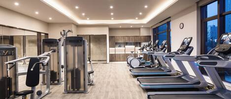 A modern gym with treadmills, weight machines, and a large mirror.