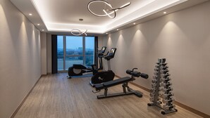 A modern gym with exercise equipment, large windows, and a wooden floor. - Citadines New District Wuxi (Wuxi)