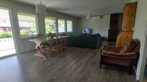 A spacious living room with a wooden dining table, chairs, a sofa, and a TV. - Lagomhuset - A Peaceful Holiday In Swedish Lapland (Vidsel)