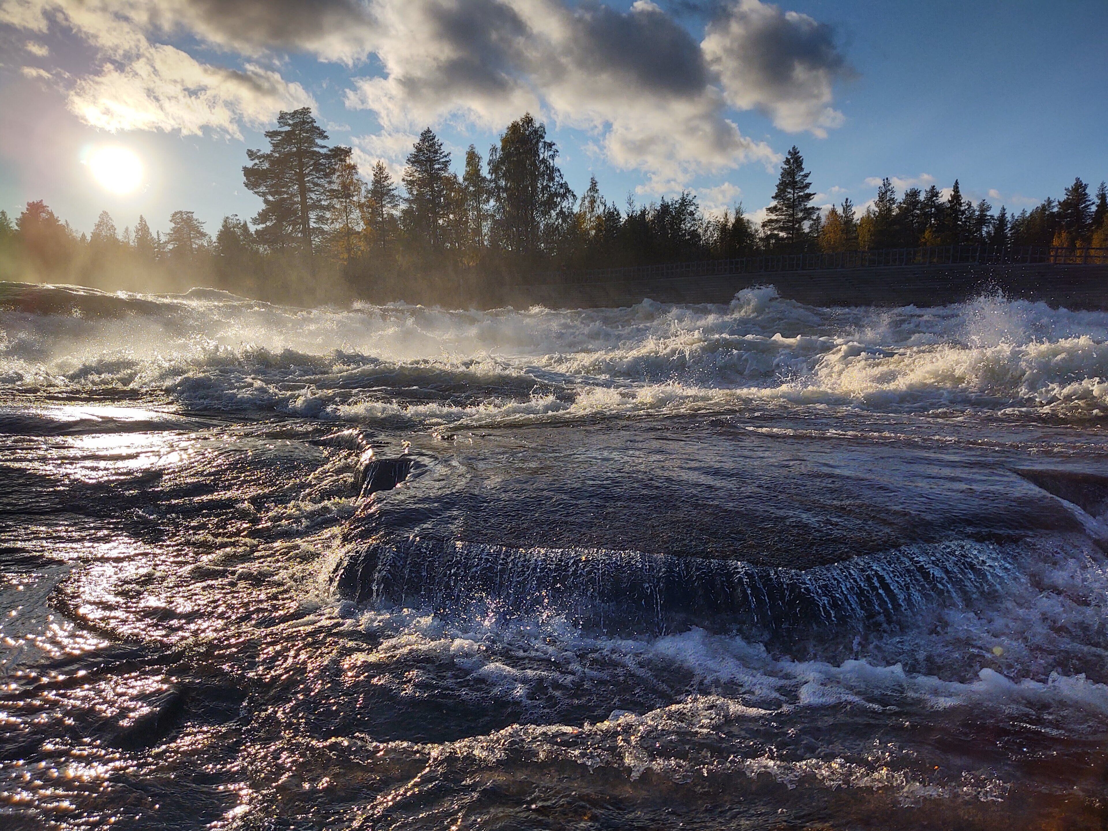 A river with turbulent water and sunlight reflecting off the surface.