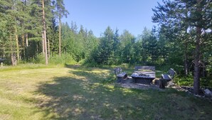 A forested campsite with a picnic table and benches. - Lagomhuset - A Peaceful Holiday In Swedish Lapland (Vidsel)