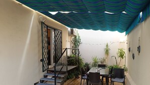 A covered patio area with a table and chairs, a staircase, and potted plants. - Apartment Huerta del Obispo (Cádiz)
