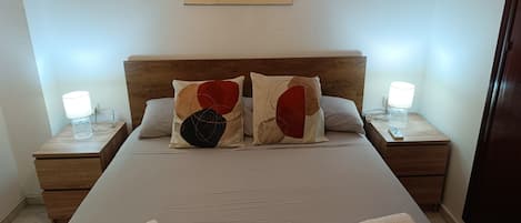 A neatly made bed with two pillows, two bedside tables with lamps, and a framed artwork above the bed.