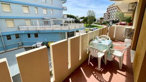 Ein Balkon mit Tisch und Stühlen, mit Blick auf ein blaues Gebäude mit zahlreichen Fenstern und Balkonen.