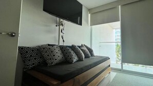A modern living room with a sofa set, a mounted TV, and a sliding glass door leading to a balcony. - Aria Ocean 188 Flamingos (Nuevo Nayarit)