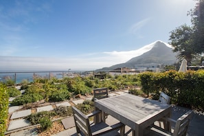 Relax on a serene patio surrounded by lush greenery and enjoy breathtaking views of the coastal area.