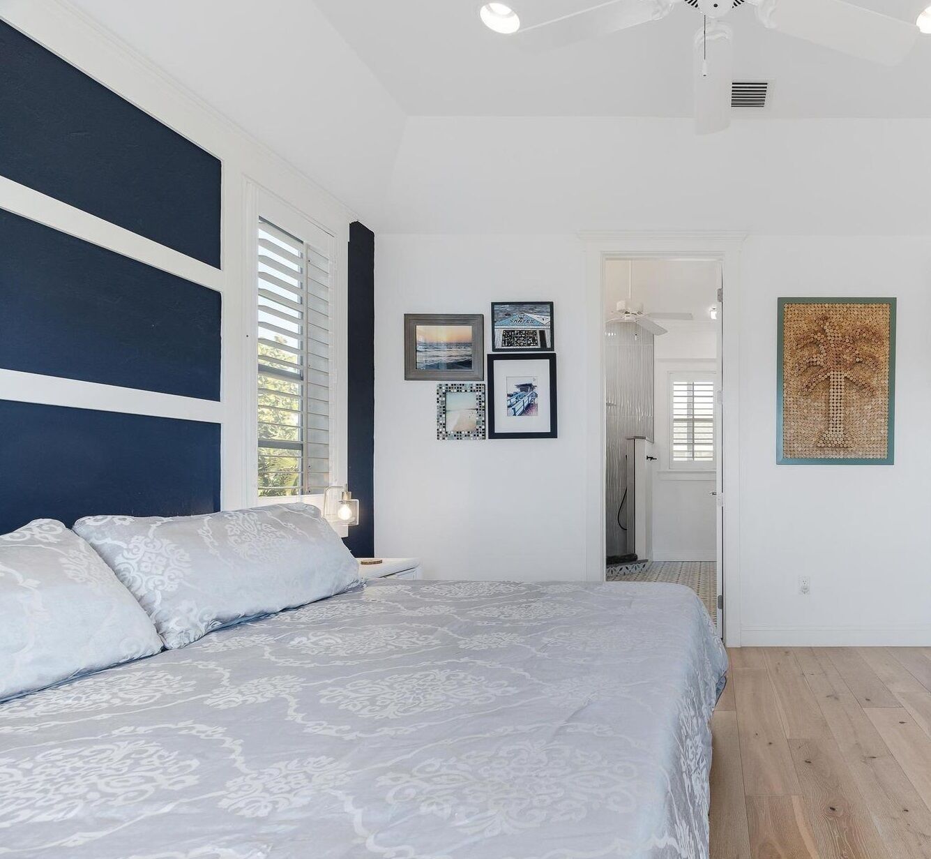 Un dormitorio con una cama grande, un ventilador de techo y cuadros en la pared.