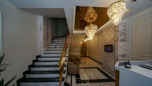 A modern hotel lobby with a marble staircase, a reception desk, and a large chandelier. - Alkan Palace Hotel (Kesan)