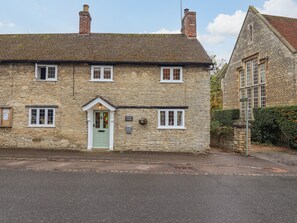 A stone cottage with a green door, multiple windows, and a sign indicating 'Waylade Cottage'.