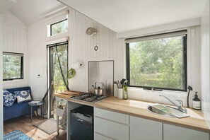 Een koelkast, een kookplaat, kookgerei, borden en bestek