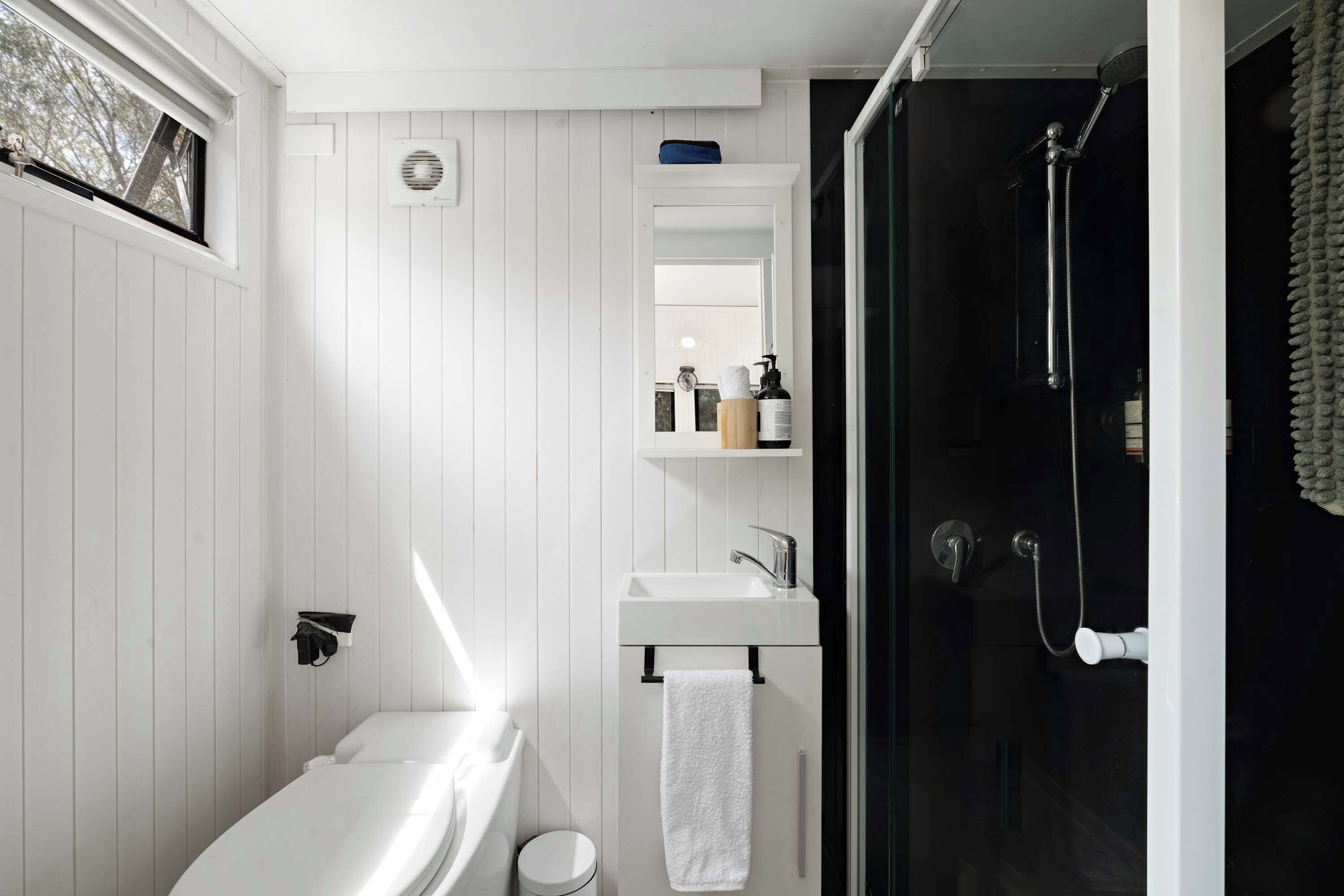 A modern bathroom with a white vanity, a glass shower enclosure, and a white toilet.