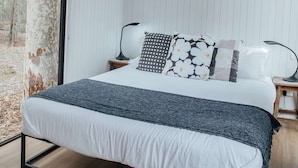 Une chambre moderne avec un grand lit, des murs blancs, une fenêtre et un appareil de climatisation.