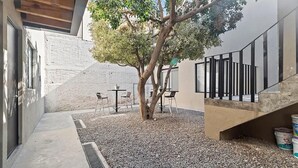 Un patio al aire libre con un árbol, mesas y sillas.