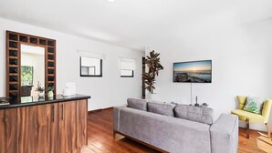 Una sala de estar moderna con un sofá gris, piso de madera, un armario de madera y un sillón amarillo.