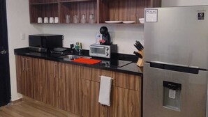 Una cocina moderna con armarios de madera, un refrigerador de acero inoxidable, horno empotrado y ventilador de techo.