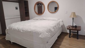 Un dormitorio con cama, dos espejos redondos, una mesita de noche con lámpara y un armario.
