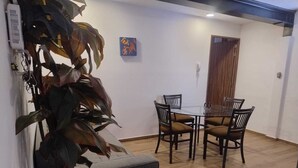 Un comedor con una mesa redonda y sillas, una planta en maceta y una puerta de madera.