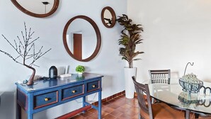 Ein Essbereich mit einem Glastisch, Stühlen, einem blauen Schrank mit Schubladen und drei hölzernen Wandspiegeln.