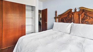 Ein Schlafzimmer mit einem Holz-Kopfteil, einer weißen Bettdecke und einem Schrank mit Schiebetüren.