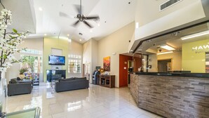 A spacious lobby with a reception desk, seating area, and a television screen. - Metro Chandler Extended Stay (Chandler)