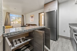 A compact kitchen with a built-in refrigerator, a countertop with a sink, and a dining area with a sofa. - Metro Chandler Extended Stay (Chandler)