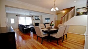 A dining area with a table set for six, a sofa, and a fireplace. - 4 Bedrooms Luxury  Location-  Houston River Oaks (Houston)