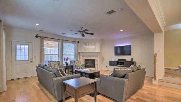 A living room with a fireplace, a ceiling fan, and a flat-screen TV mounted on the wall. - 4 Bedrooms Luxury  Location-  Houston River Oaks (Houston)