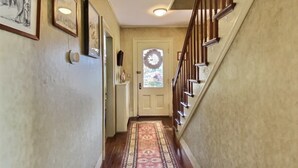 A hallway with a wooden staircase, a patterned rug, and framed pictures on the walls. - Historic Colonial...Close to Village Green (Litchfield)