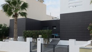 A modern building with a black facade, white walls, and a palm tree. - Golf & Sea Top location (Villamartin)