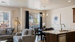 Een moderne woonkamer met een grijze bank, een salontafel, en een eethoek met een keukeneiland.