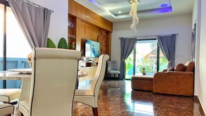 Un saló modern amb sòl de marbre, un sofà, zona de menjador amb cadires, televisió i un balcó amb vistes.
