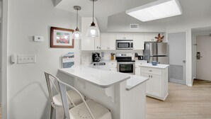 Una cocina moderna con armarios blancos, una isla central y electrodomésticos de acero inoxidable.