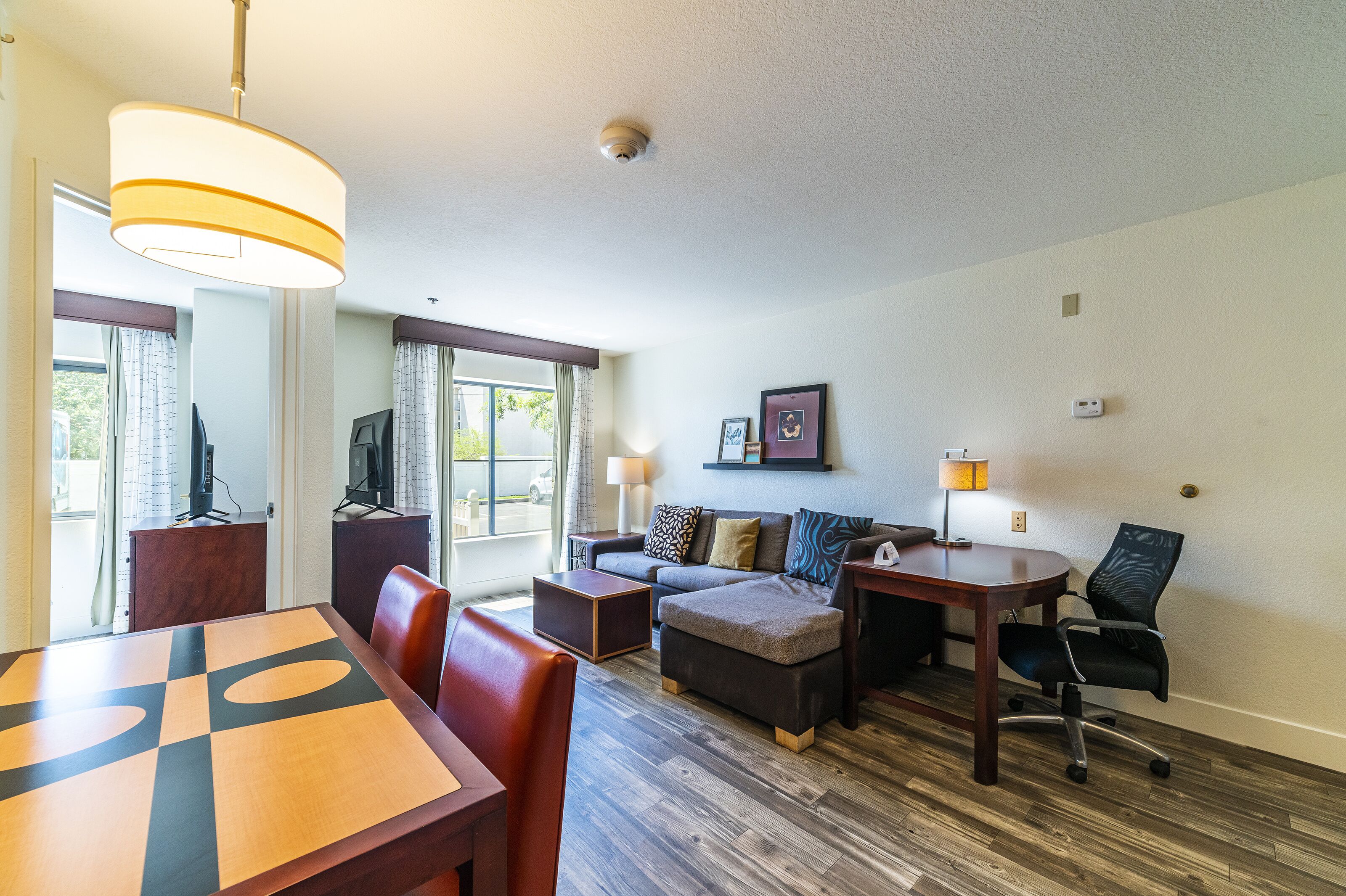 A modern hotel room with a dining area, a sofa set, a small table, and a television.