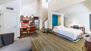 A hotel room with a bed, a desk, a chair, a small table, a sofa, a ceiling fan, and a kitchenette. - Metro Phoenix Extended Stay (Phoenix)