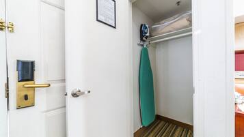 A hotel room with a white door, a security card reader, an iron, and a green towel hanging on the wall.