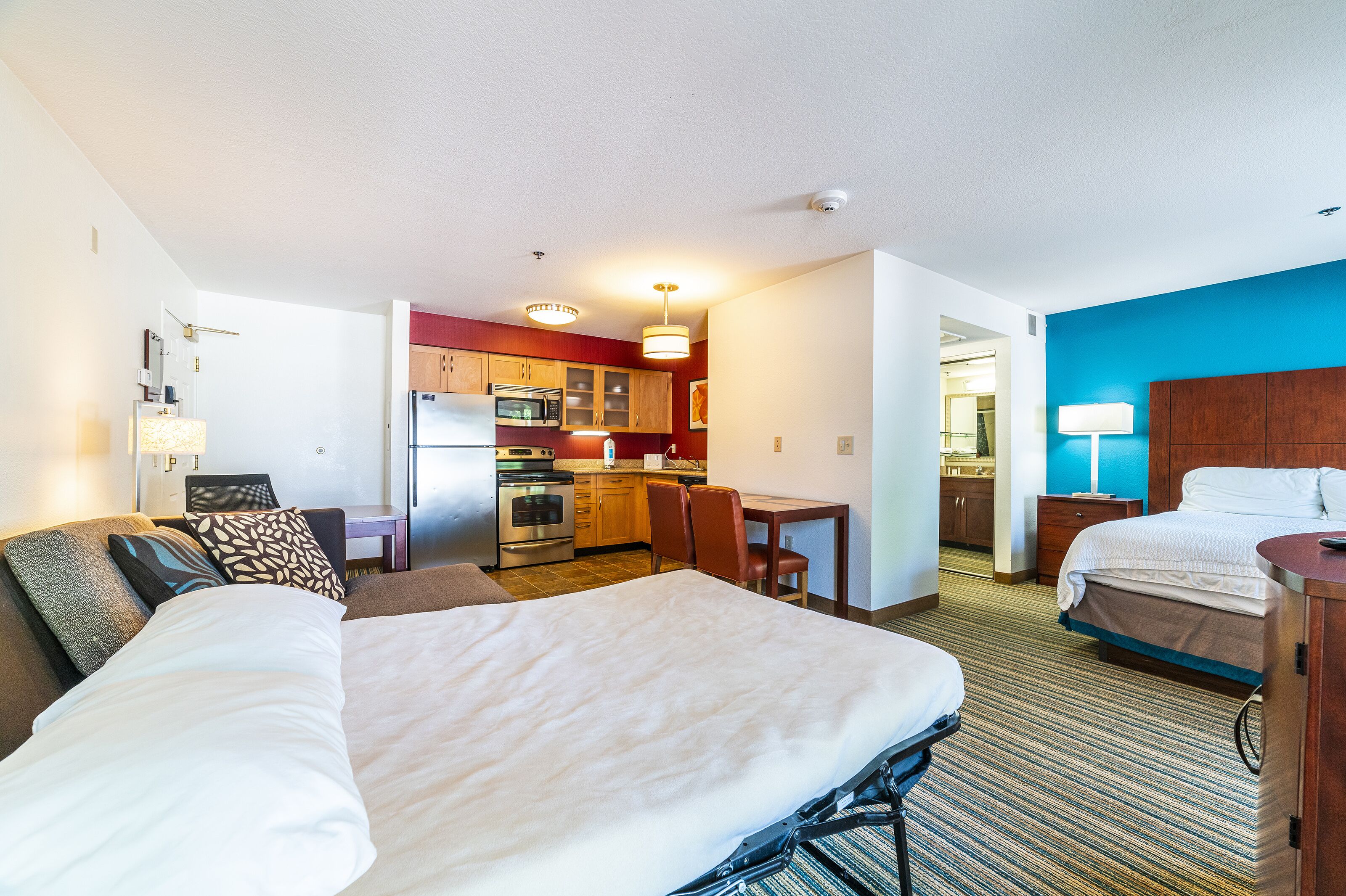 Une chambre d’hôtel avec deux lits, une kitchenette, un coin repas et une salle de bain.
