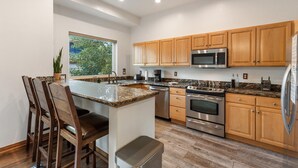 A modern kitchen with wooden cabinets, a granite countertop, stainless steel appliances, and a large window providing natural light. - Luxury Home-Walk to everything in Frisco. Hot tub, ski, fireplace 3BD, 3.5BA



 (Frisco)