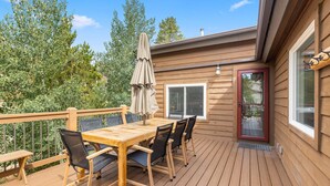 A wooden deck with a table and chairs, a covered umbrella, and a glass door. - Luxury Home-Walk to everything in Frisco. Hot tub, ski, fireplace 3BD, 3.5BA



 (Frisco)