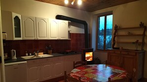 Una cocina acogedora con armarios de madera, una estufa y una mesa de comedor con mantel colorido.