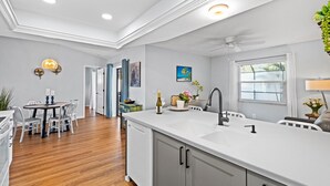 Una cocina moderna con una isla grande, armarios blancos y lavavajillas integrado.