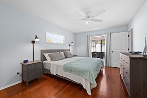 A bedroom with a bed, nightstands, a dresser, a ceiling fan, and a window with blinds.