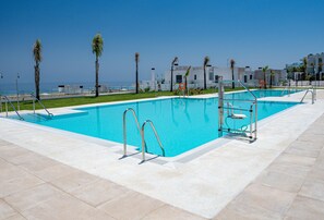A rectangular swimming pool with clear blue water, surrounded by a tiled deck and palm trees. - The Links II Sea View 2473 La Alcaidesa Golf (La Alcaidesa)
