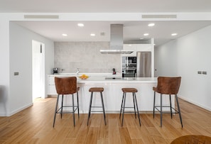 A modern kitchen with a central island, three bar stools, and a stainless steel refrigerator. - The Links II Sea View 2473 La Alcaidesa Golf (La Alcaidesa)