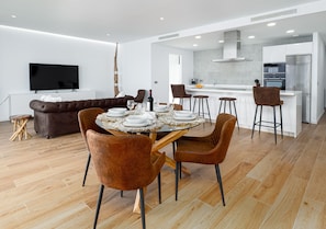 A modern dining area with a round table, brown chairs, and a sofa in the background. - The Links II Sea View 2473 La Alcaidesa Golf (La Alcaidesa)