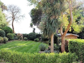 Stroll through a serene garden featuring a weeping willow and a beautifully manicured lawn.