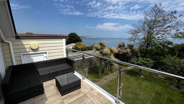 A balcony with a glass railing overlooking a garden and the sea. - Littlestairs (Shanklin)