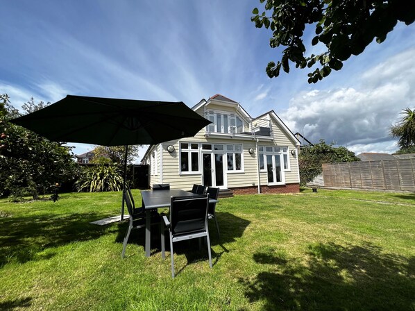 A house with a patio, a table, and chairs under an umbrella.
