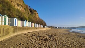 A beach with a row of colorful beach huts along the shore. - Littlestairs (Shanklin)