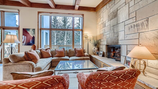 A cozy living room with a stone fireplace, a large window, and a comfortable seating area. - Ski-in Condo w Vail Views near Gondola, TT5C (Vail)